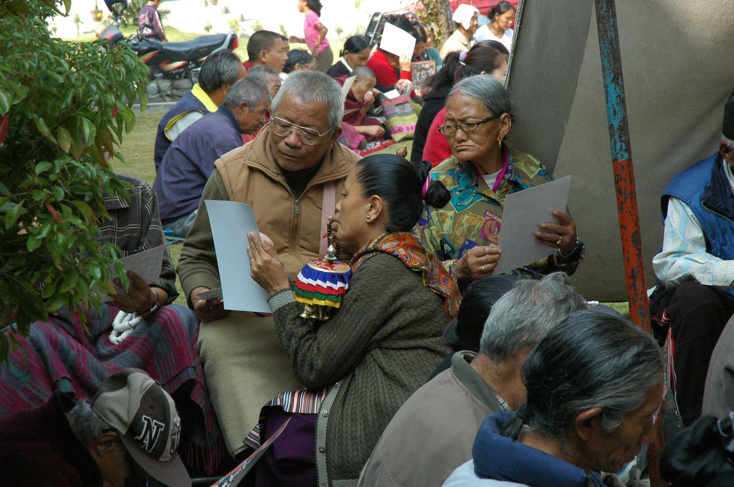 People read papers at an outdoor community gathering.
