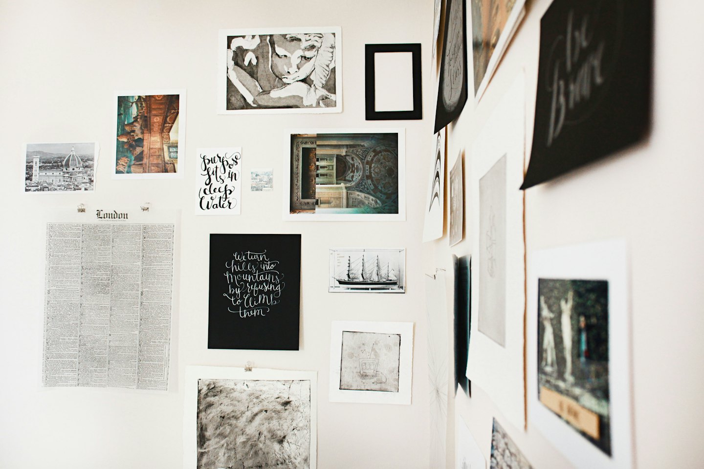 Unframed prints and photos displayed on a light wall.